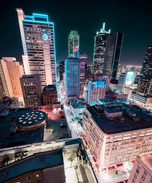 Image of the Dallas downtown skyline lit up with neon lights and a view of the At&t building.