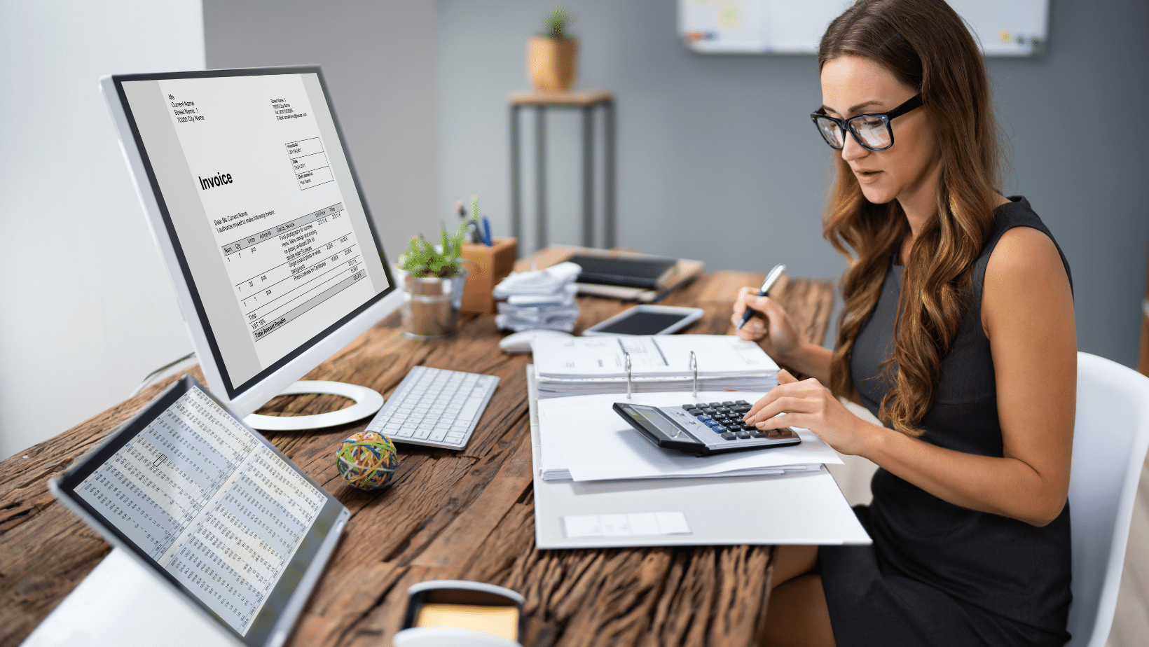 A person in a business suit sitting at a desk with a calculator.