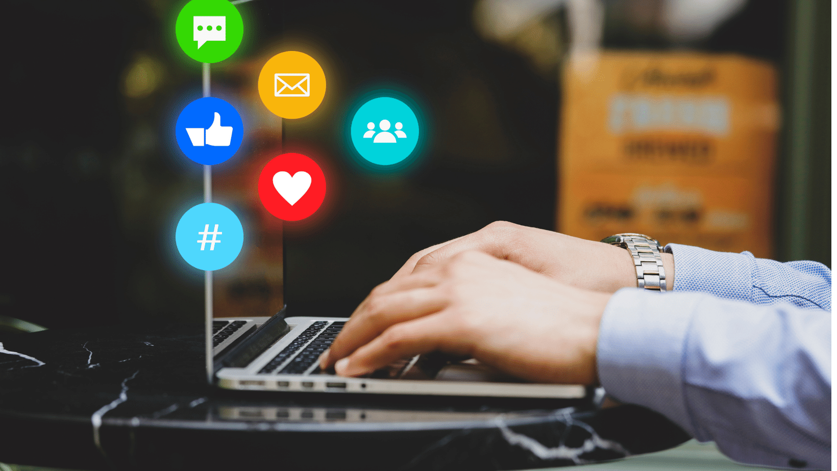 A person is typing on a laptop with social icons on it.