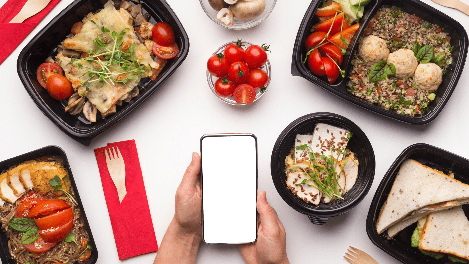 A person taking a picture of food in black containers on a white table.
