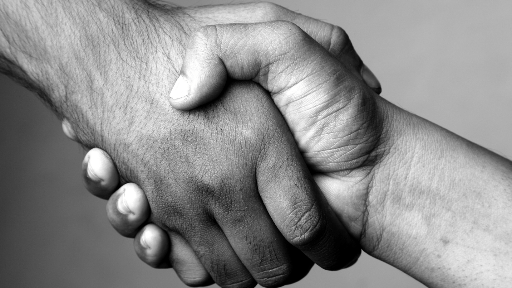 A black and white photo of two people shaking hands.