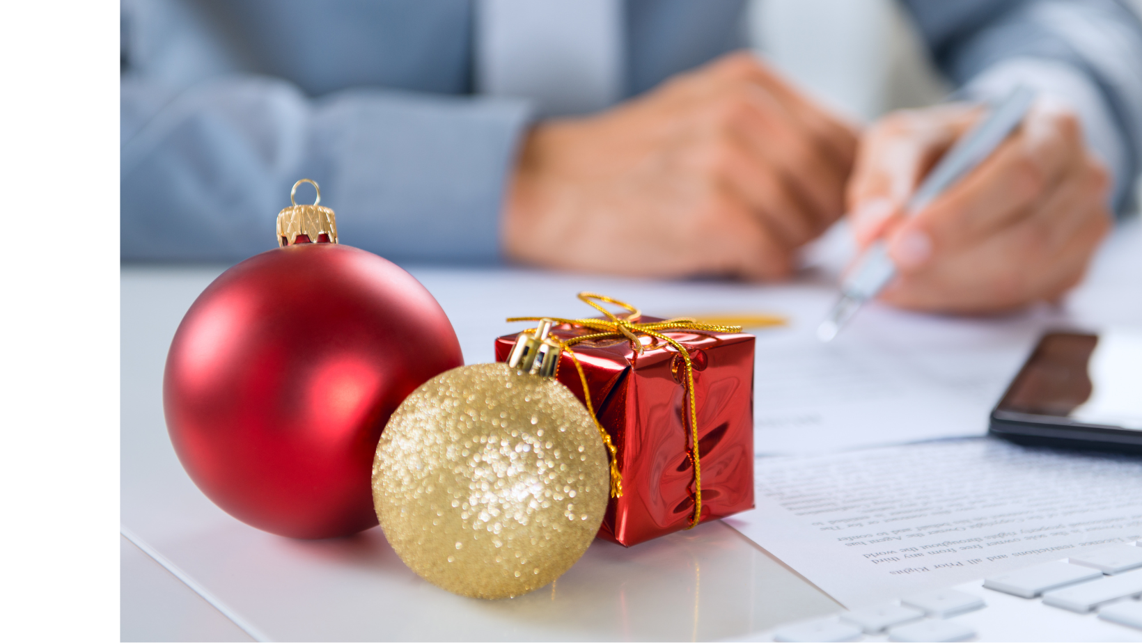 Ascend Adwerks' team member working on a Holiday PPC campaign with ornaments and a present on the table.