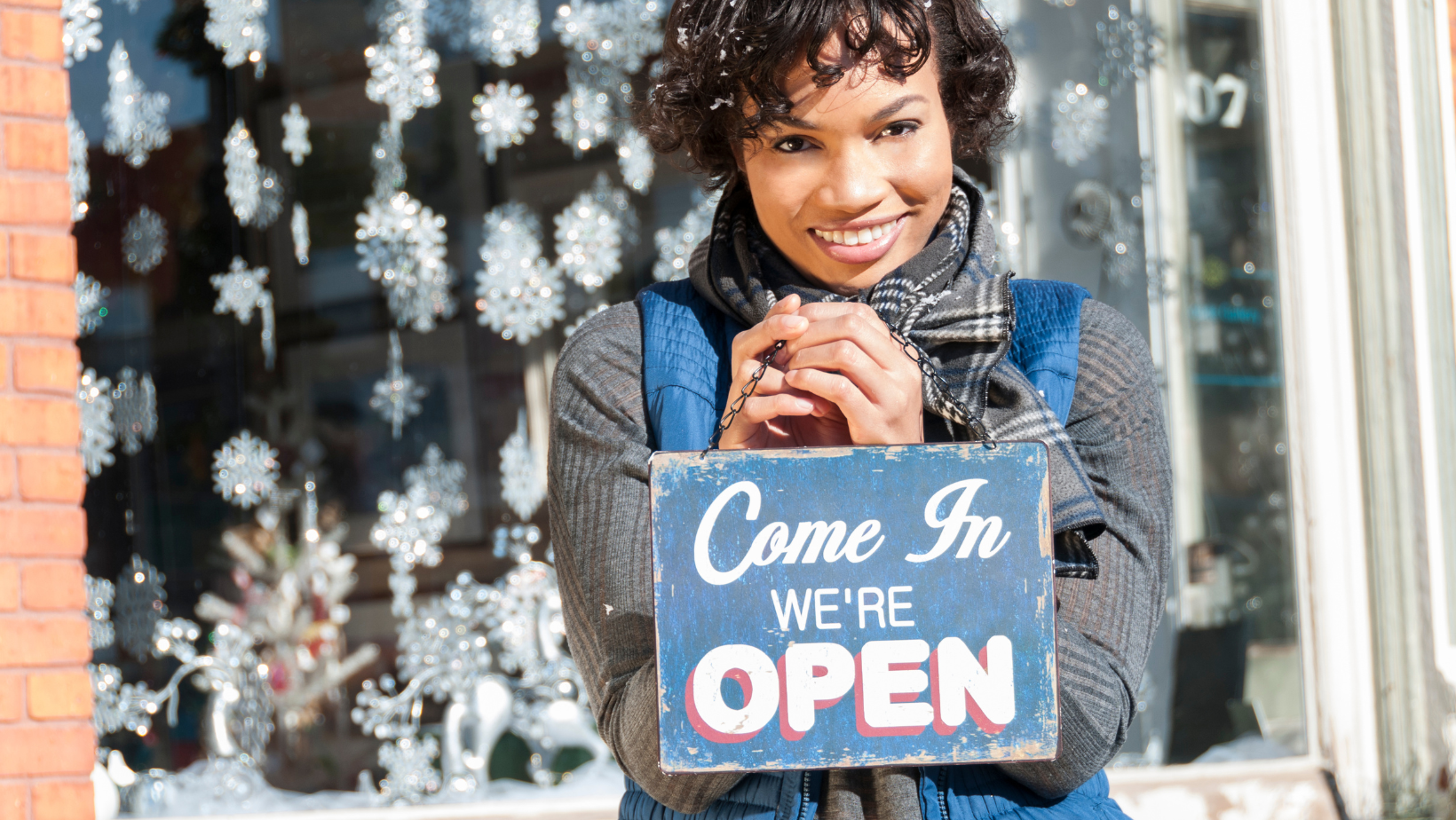 An Ascend Adwerks client is holding an open sign that says, ‘Come in, we are open.’