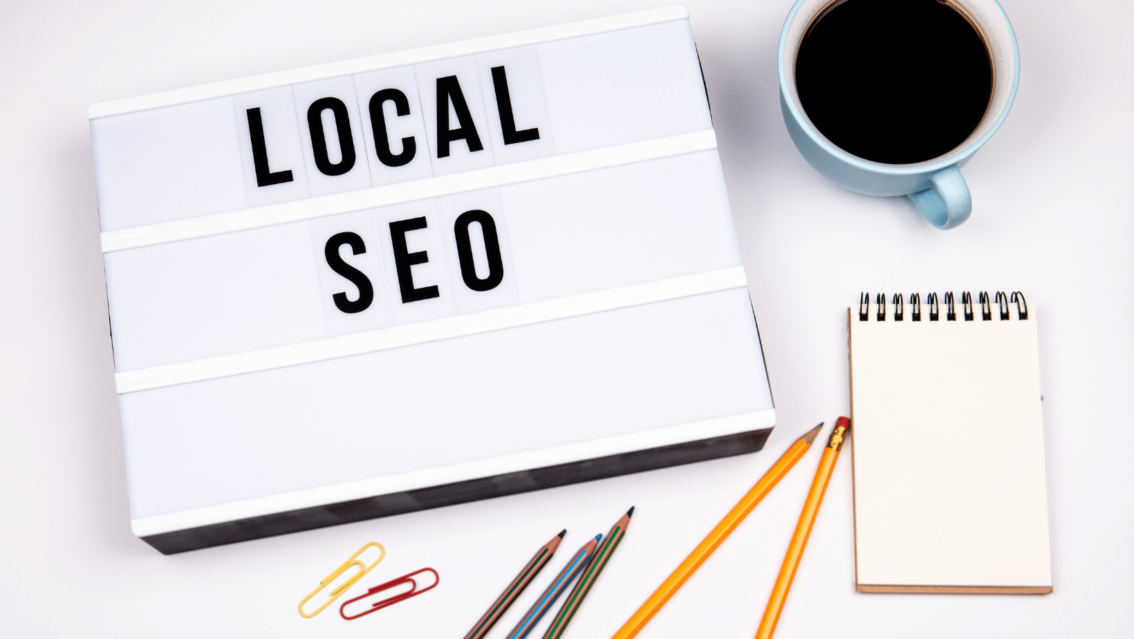 A white desk with 'Local SEO' beside a coffee cup and several office supplies.
