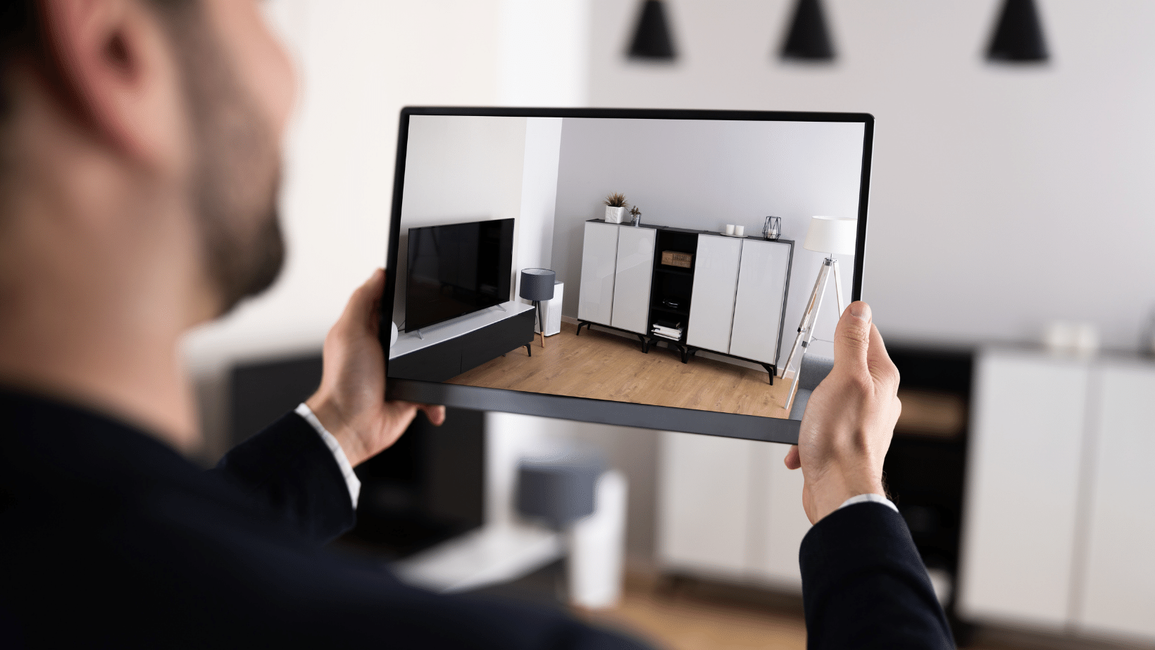 A person is holding up a tablet with an image of a living room to complete a Virtual Tour of a home.